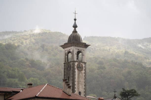 Old Church Tower in Kanal, Slovenia surrounded by houses and mountains on a foggy day An old Church Tower in Kanal, Slovenia surrounded by houses and mountains on a foggy day kanal stock pictures, royalty-free photos & images