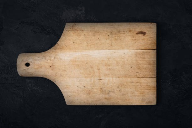 istock Wooden cutting board on dark stone concrete background, top view. 1446415557