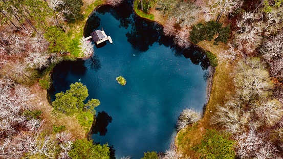 An aerial view of small dock house on lake surrounded by trees