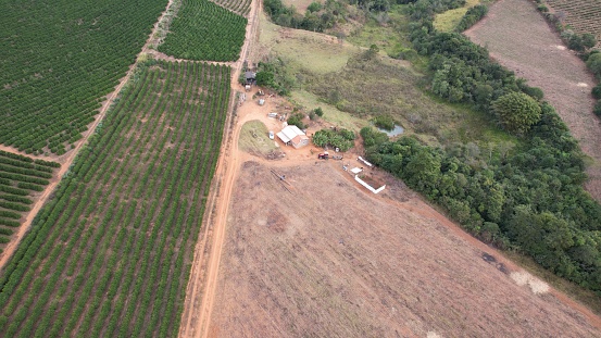 An aerial shot of an unpopulated field with dirt and trees