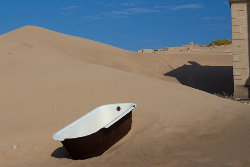 A shot of an old broked bathtub in the middle of sand hills