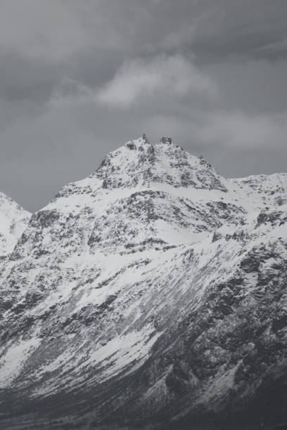 istock Vertical grayscale of a high mountain peak covered with snow under the cloudy sky 1446424385