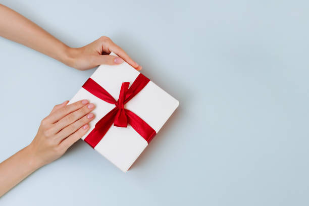 istock Women's hands hold a white with a red ribbon bow 1446425686
