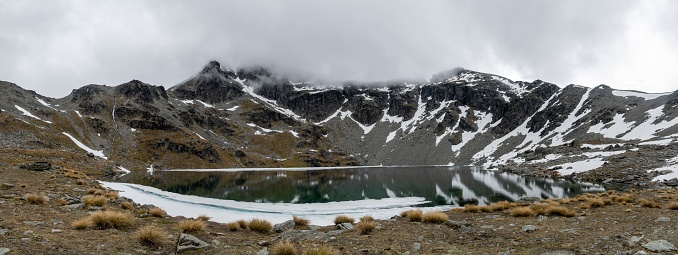 A panoramic view of Lake Alta with clouds over it in winter in Queenstown, New Zealand.