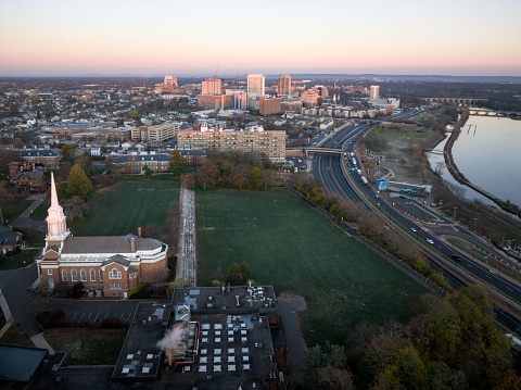 A drone view of a city skyline with buildings near the river at sunrise in New Brunswick, Rutgers, Hub City, USA