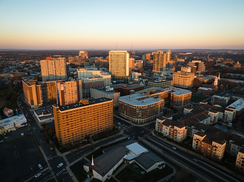 A drone view of a city skyline with buildings illuminated by sun rays at sunrise in New Brunswick, Rutgers, Hub City, USA