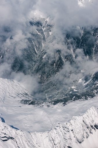 A vertical shot of mountain slope covered with snow on a cloudy day