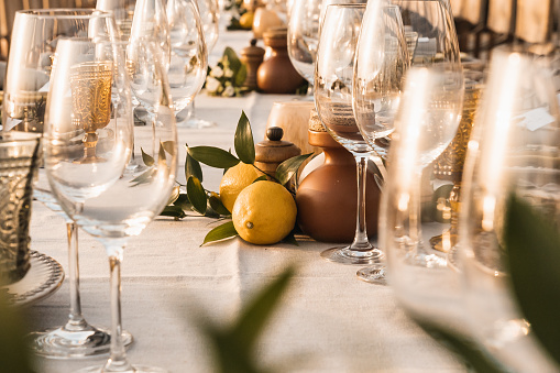 A long dinner table set up with wine glasses and lemon decorations