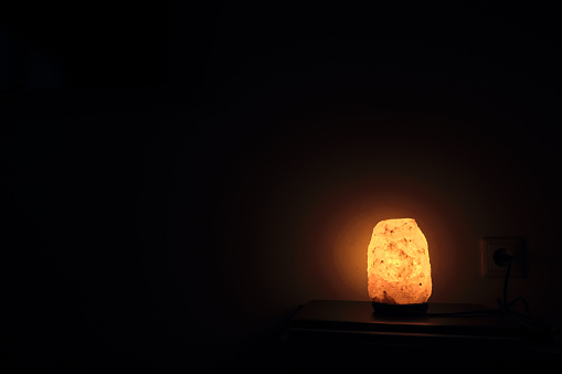Salt lamp on the table in the room glows in the night