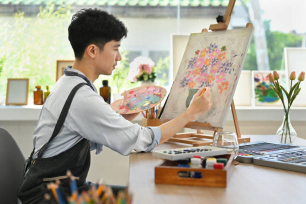 istock Satisfied man painting on easel with watercolor in comfortable art workshop. Leisure activity and creative hobby concept. 1446437697