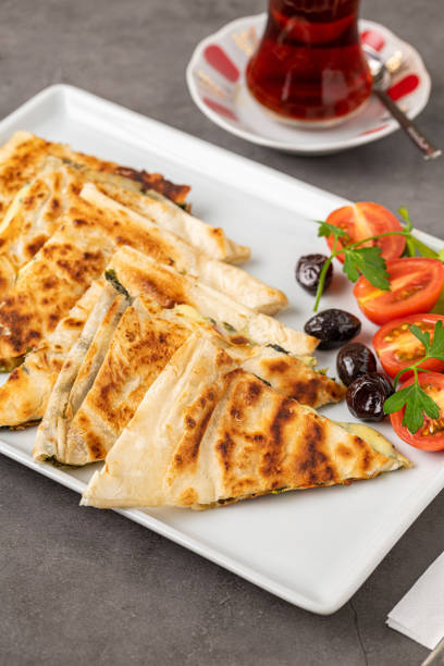 istock Traditional Turkish flatbread or Gozleme with tomatoes, olives and tea on dark stone table 1446439775