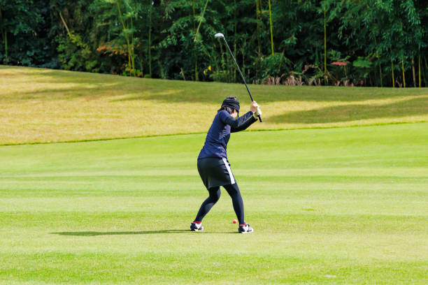 A golf course with a beautiful lawn and a woman playing