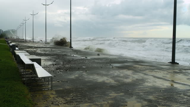 Sea waves crashing over destroyed road and coastline during stormy extreme weather