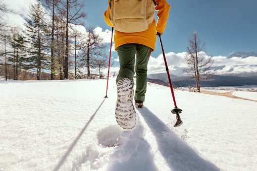 Active lifestyle girl is walking in deep snow with hiking poles. Winter vacations concept