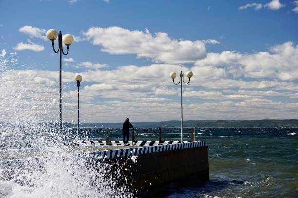 las olas rompen en un muelle en vladivostok. olas altas con salpicaduras golpean contra el muelle. clima soleado de verano en vladivostok. una tormenta en vladivostok. las olas de agua se elevan sobre el muelle. - water waterfall sky seascape fotografías e imágenes de stock