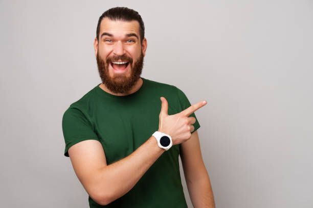 istock Young handsome man is pointing aside at the space for message beside him. 1446447341