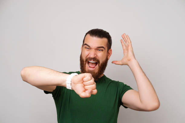 istock Bearded man is upset because he is late while looking at the watch he has got. 1446447348