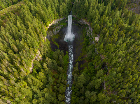 Aerial shot of a stunning waterfall in the forests close to Whistler, Canada. Tall waterfall flowing into a large crater