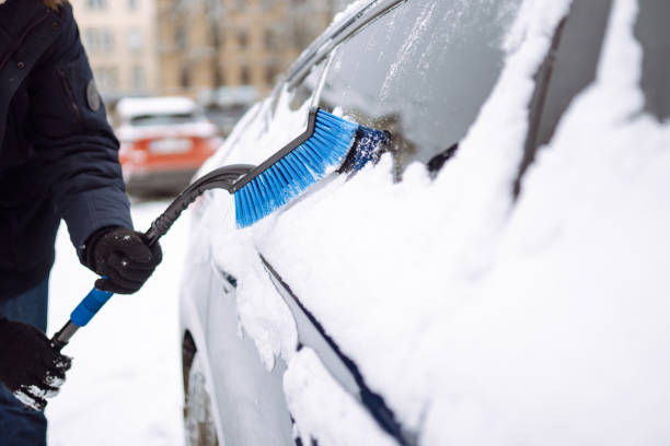 istock Young man cleaning snow from car with brush. 1446448645