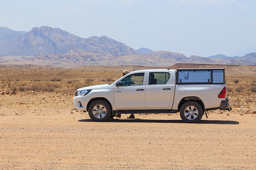 Khomas Region Capricorn, Namibia - 02 October 2018: Typical 4x4 rental car in Namibia equipped with camping gear and a roof tent driving on a dirt road through the Namibian wilderness.