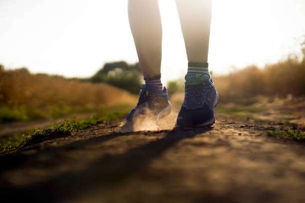 Female athletic legs and dust from the trail close up.
