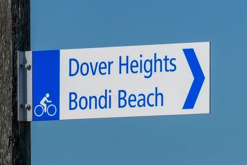 Sign pointing the direction to Dover Heights and Bondi Beach.  The sign is located on Old South Head Road near Watsons Bay, Sydney. The sign is attached to an aging, wooden telegraph pole. This image was taken on a sunny afternoon in early Summer