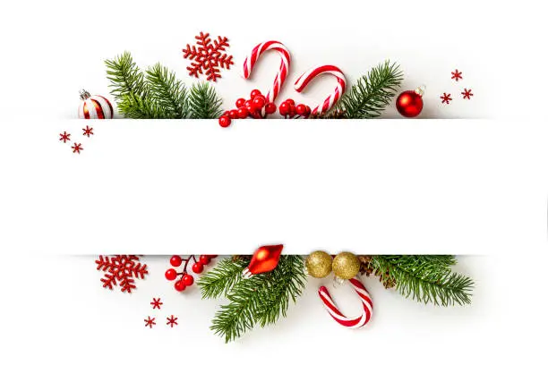 Top view of a bunch of pine branches, candy canes and christmas ornaments with copy space on white background.  Ideal for texts, invitations or greeting cards.