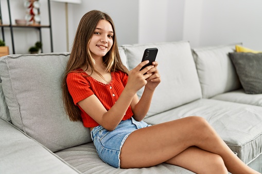 Adorable girl smiling confident using smartphone at home