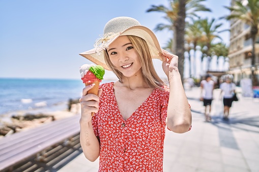 Young chinese girl smiling happy eating ice cream at the promenade.