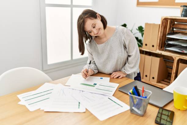 istock Brunette woman with down syndrome working with documents at business office 1446458343