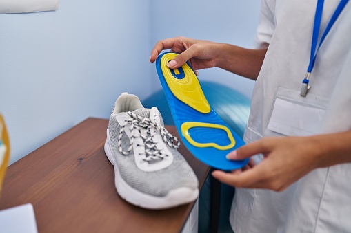 Young blonde woman podiatrist holding insole at clinic