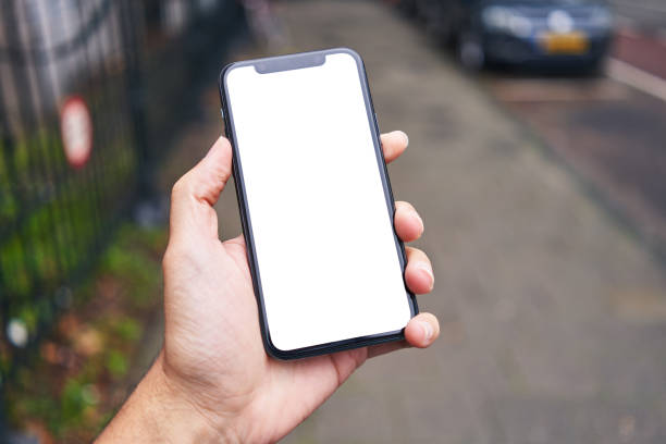 istock Man holding smartphone showing white blank screen at street 1446459685