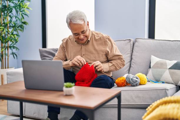 istock Senior man having online sew lesson sitting on sofa at home 1446459921