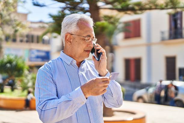 istock Senior man talking on the smartphone and using credit card at park 1446459942