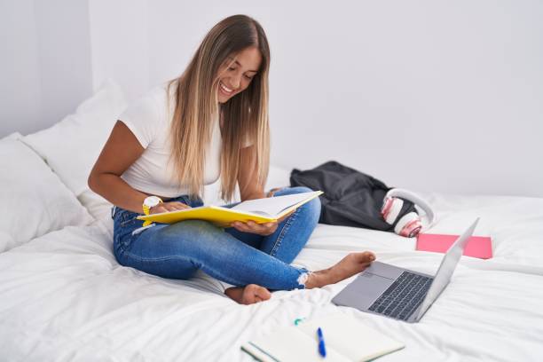 istock Young beautiful hispanic woman student reading book studying on bed at bedroom 1446460202