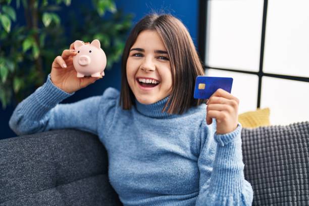Young hispanic woman holding piggy bank and credit card smiling and laughing hard out loud because funny crazy joke. Young hispanic woman holding piggy bank and credit card smiling and laughing hard out loud because funny crazy joke. people laughing hard stock pictures, royalty-free photos & images
