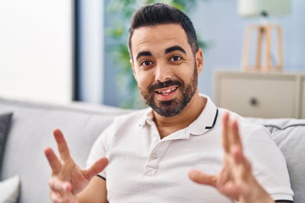 istock Young hispanic man sitting on sofa talking at home 1446461196