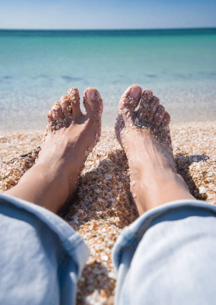 Women's legs in shells on the background of the Azure Sea stock photo