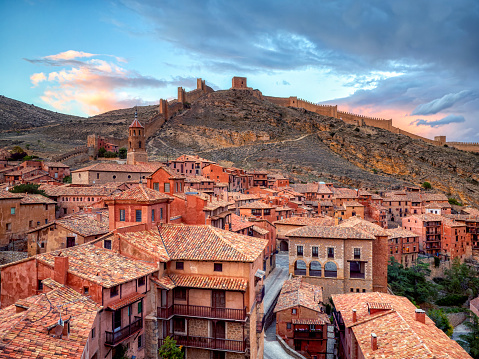 Views of Albarracin at sunset with its walls and its cathedral in the foreground.