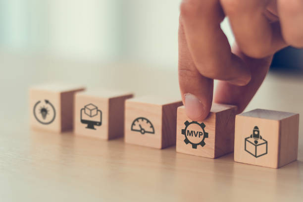 istock MVP, minimum viable product concept for lean startup. Life cycle of product development. Analysis and market validation. Hand puts wooden cubes with abbreviation MVP and learn, build, measure icons. 1446470674