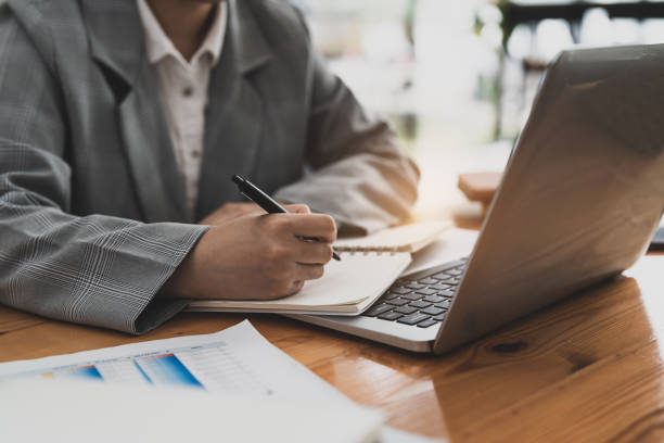 istock Young woman hand taking notes with laptop at the table office. 1446472122