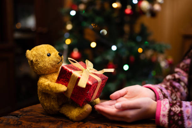 テディベアからクリスマスプレゼントを受け取る女の子 - イルミネーション　子ども ストックフォトと画像