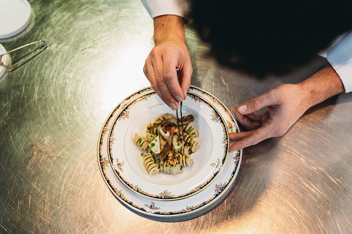 A chef is finishing the preparation of the plate. He's decorating the plate just before the serving.