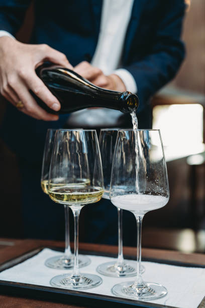 a waiter is pouring prosecco into glasses at the restaurant - champagne champagne flute pouring wine imagens e fotografias de stock