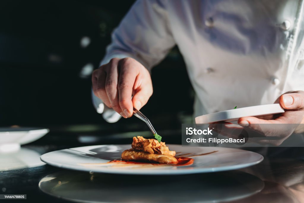 A chef is finishing the preparation of the plate A chef is finishing the preparation of the plate. He's decorating the plate just before the serving. Gourmet Stock Photo