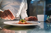 A chef is finishing the preparation of the plate