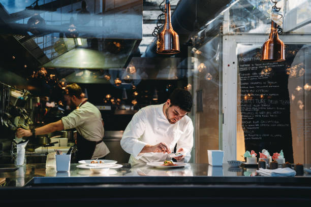 a chef is cooking in his restaurant's kitchen - storkök bildbanksfoton och bilder