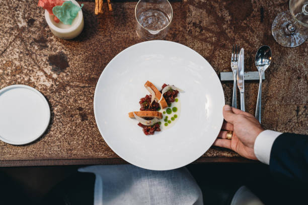 A waiter is serving a plate in an high-end restaurant stock photo