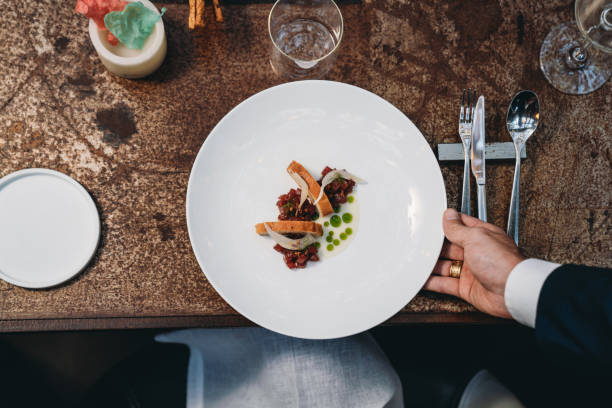 a waiter is serving a plate in an high-end restaurant - dining table food elegance imagens e fotografias de stock