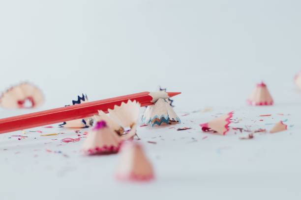 istock Closeup of a sharpened red pencil with pencil shavings on white surface 1446479316